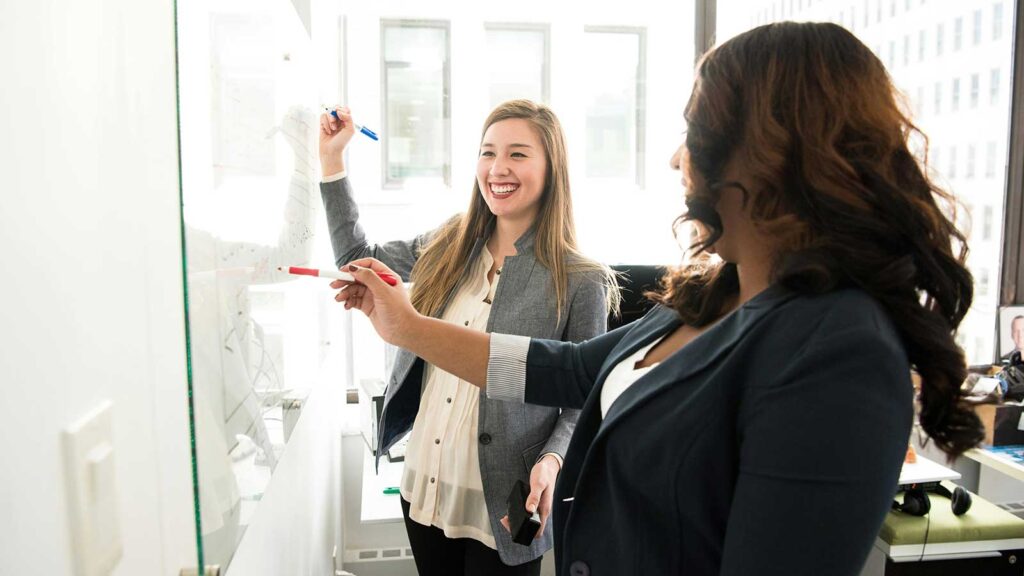 a woman pointing at a whiteboard with a marker discussing Process of a Phase I Environmental Site Assessment