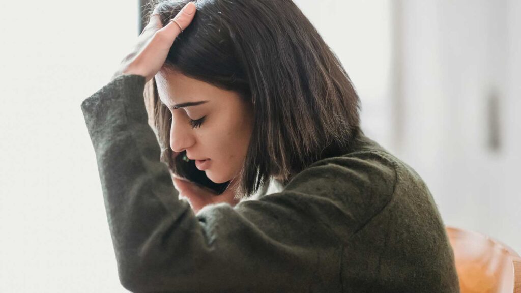 a woman holding her head and talking on the phone a image to support the need Insurance Claims